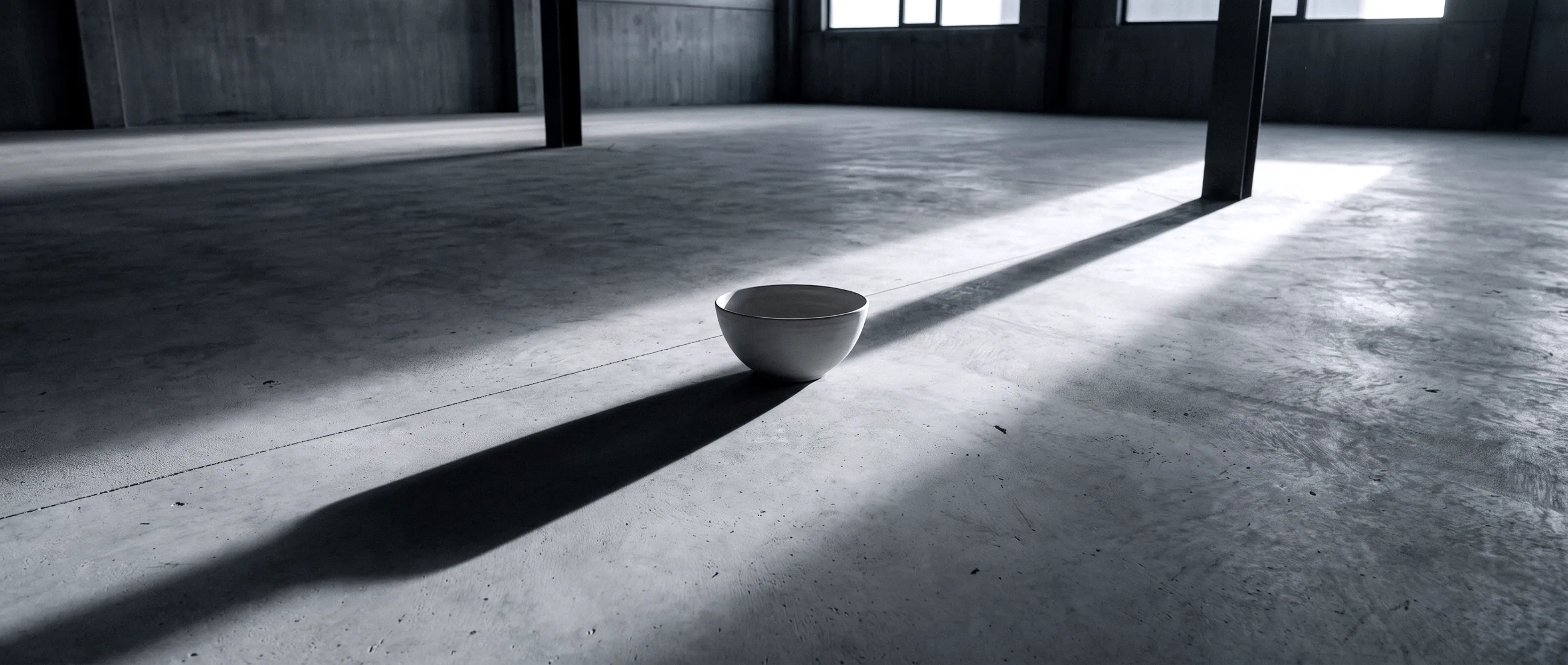 One bowl alone on a concrete floor in a shaft of light